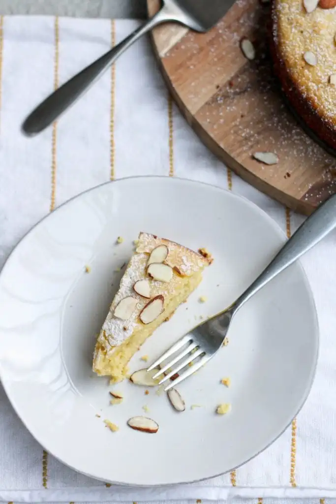 a slice of citrus almond ricotta cake on a white plate with a fork