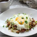 low carb cabbage and corned beef hash on a white plate with a cup of coffee