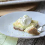 keto coconut lime bar topped with whipped cream on a white plate with a fork