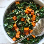 roasted sweet potato and kale salad in a white serving bowl with a spoon